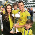 Bruno Teles, esposa e dois filhos comemora no gramado exibindo o troféu e medalha -